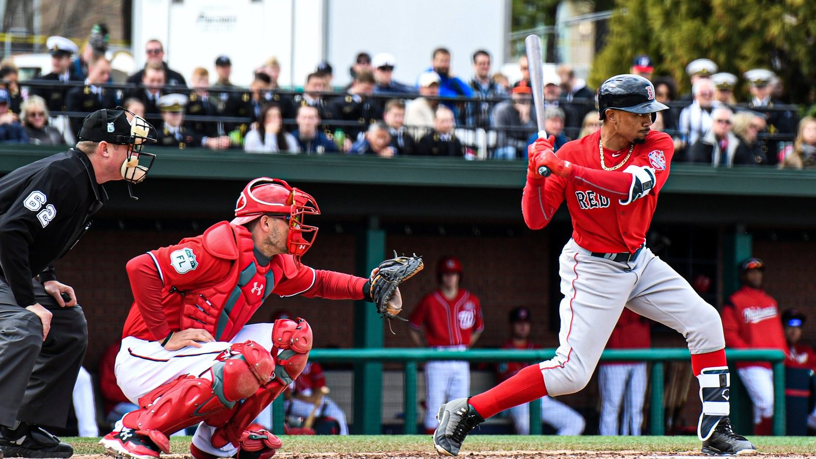Mookie Betts finishing his swing at Terwilliger Brothers Field, midshipmen watching from a few feet behind the dugout